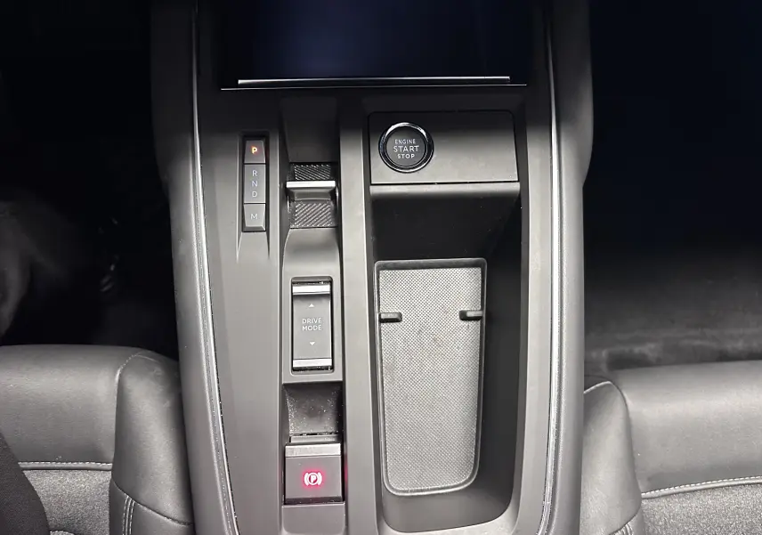 Vue plongeante sur la console centrale noire du Citroën C5 Aircross hybride 2025 avec boutons de démarrage et boîte auto.