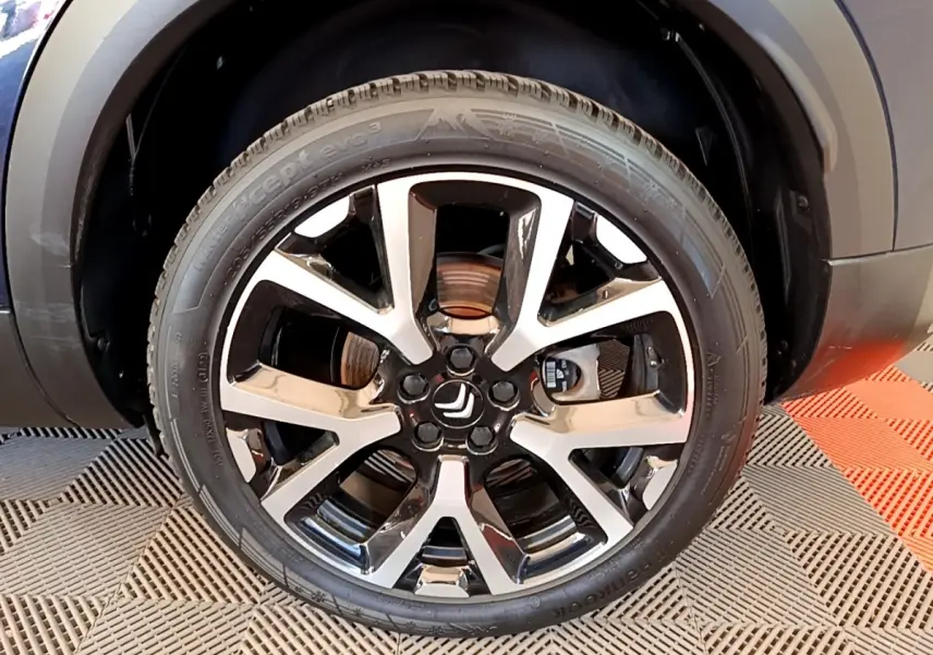 Gros plan sur la roue avant droite du Citroën C5 Aircross 2023 avec jante alliage bicolore noire et argentée.