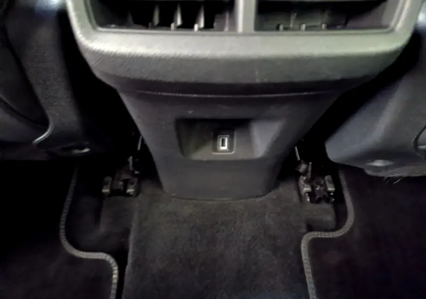 Vue rapprochée de la console arrière noire du Citroën C5 Aircross 2023 avec prise USB et tapis de sol sombre.