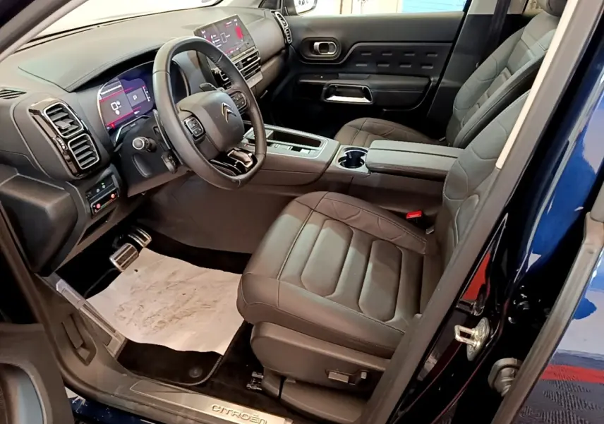 Intérieur avant droit du Citroën C5 Aircross 2023 bleu, avec sièges cuir noirs et tableau de bord digital lumineux.