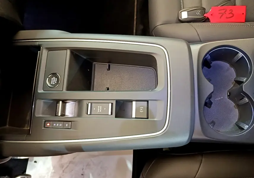 Vue plongeante sur la console centrale noire du Citroën C5 Aircross 2023 avec bouton start/stop et porte-gobelets.