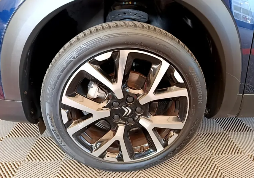Gros plan sur la roue avant gauche du Citroën C5 Aircross 2023, jante alliage bicolore avec logo Citroën central.
