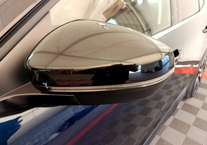 Gros plan sur le rétroviseur droit noir brillant du Citroën C5 Aircross 2023, avec reflet de l'environnement intérieur.