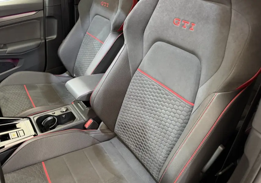 Gros plan sur les sièges avant gris foncé avec surpiqûres rouges et logo GTI brodé dans l’habitacle d’une Volkswagen Golf GTI Clubsport.