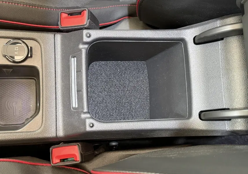 Vue plongeante sur la console centrale noire de la Volkswagen Golf GTI Clubsport 2022 avec surpiqûres rouges et prise 12V.