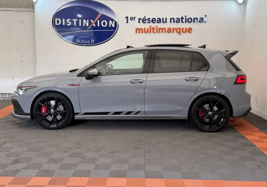 Vue de profil côté gauche d'une Volkswagen Golf GTI Clubsport 2022 gris foncé avec jantes noires et étriers rouges.