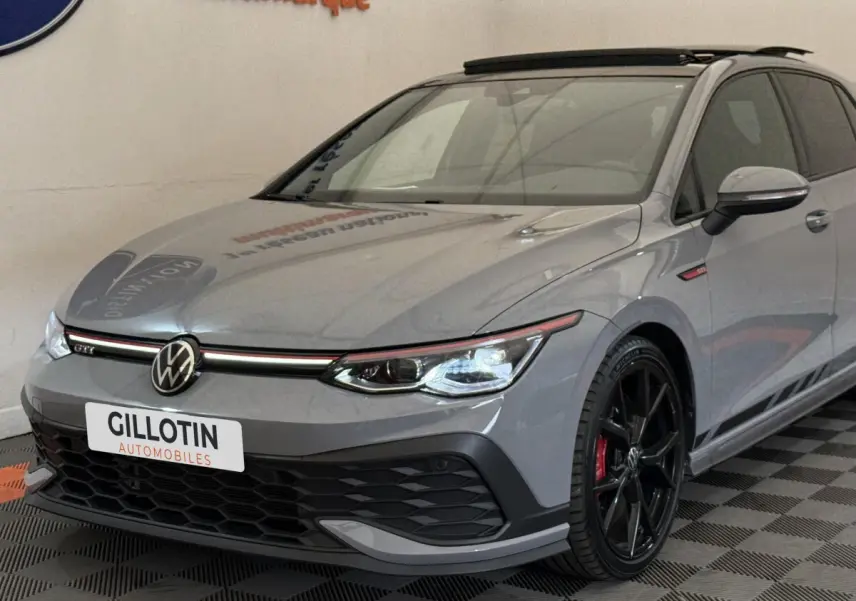 Vue 3/4 avant droite d'une Volkswagen Golf GTI Clubsport gris foncé avec jantes noires et détails rouges.