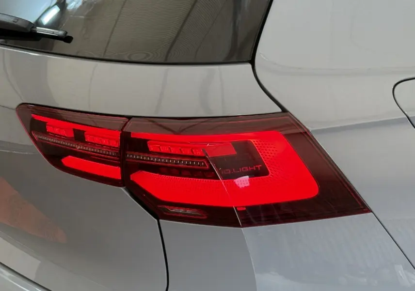 Gros plan sur le feu arrière droit rouge d’une Volkswagen Golf gris foncé, vue de l’arrière côté droit.