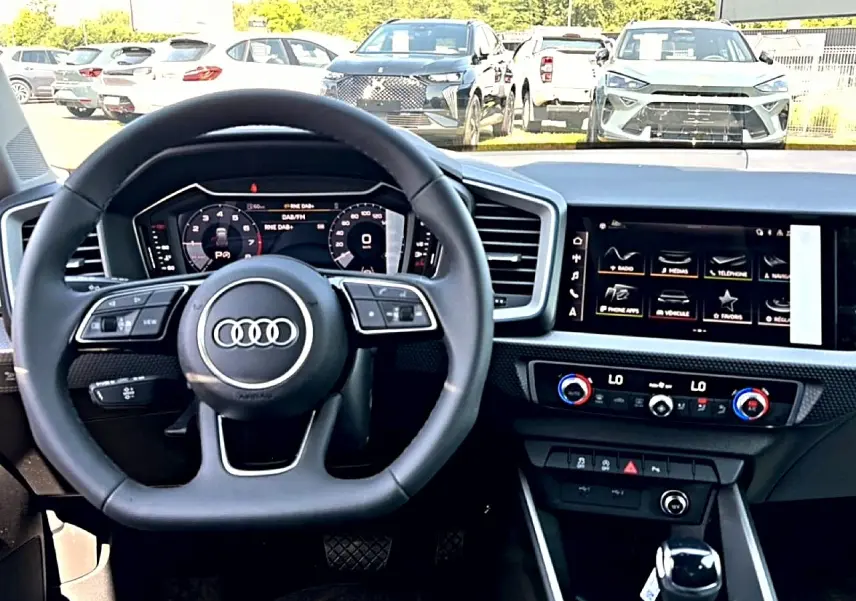 Vue intérieure du tableau de bord de l'Audi A1 Sportback 2026 avec volant multifonction et écran tactile central.