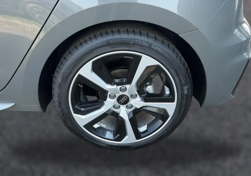 Gros plan sur la roue arrière droite d’une Audi A1 Sportback gris chronos avec jante alu bicolore distinctive.