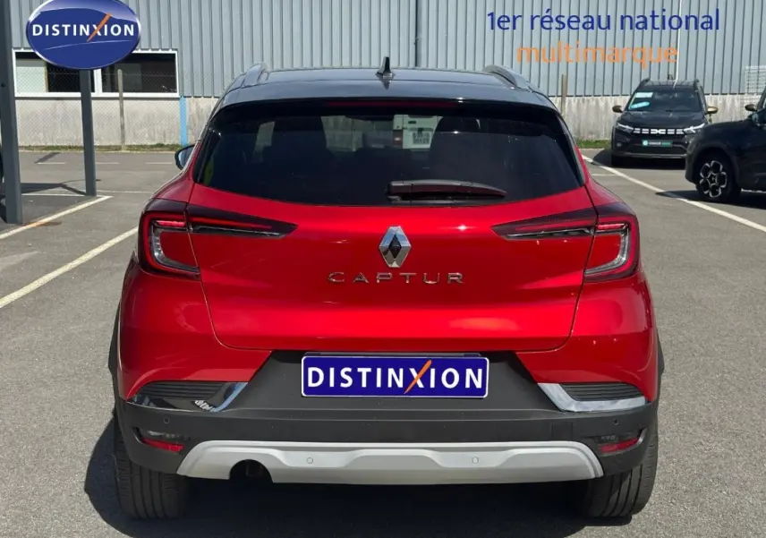 Vue arrière d’un Renault Captur 2024 rouge flamme nacré avec toit noir et feux arrière LED distinctifs.