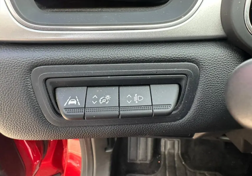 Gros plan sur les boutons de réglage d'assistance et éclairage du tableau de bord d'un Renault Captur Rouge Flamme nacré.