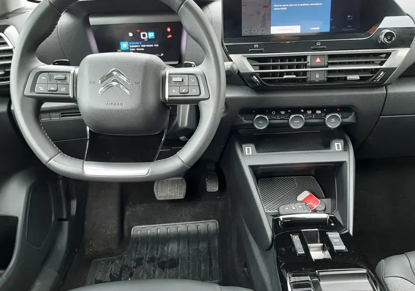 Vue intérieure du poste de conduite de la Citroën C4 Hybrid 2024, avec volant multifonction et écran tactile central.