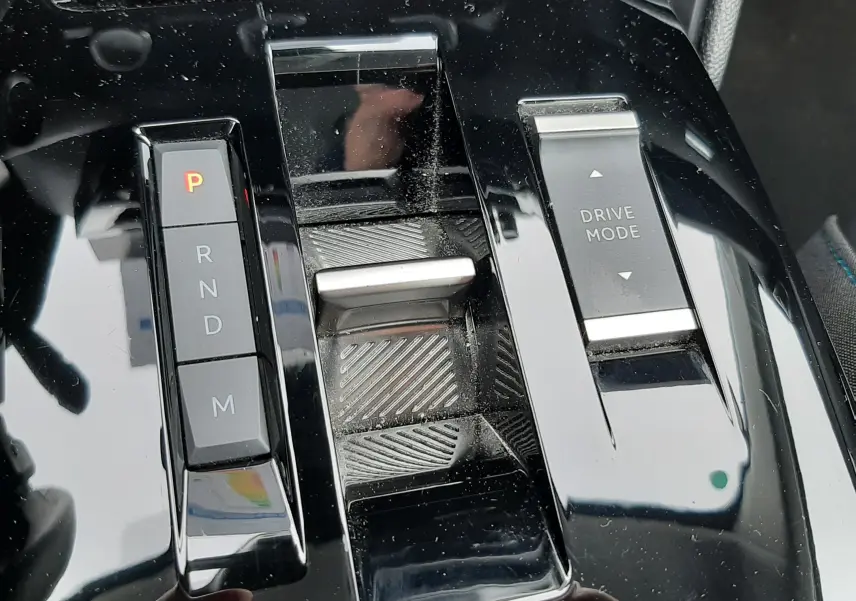 Gros plan sur la console centrale noire brillante de la Citroën C4 Hybrid 136, avec commandes de boîte auto et mode de conduite.