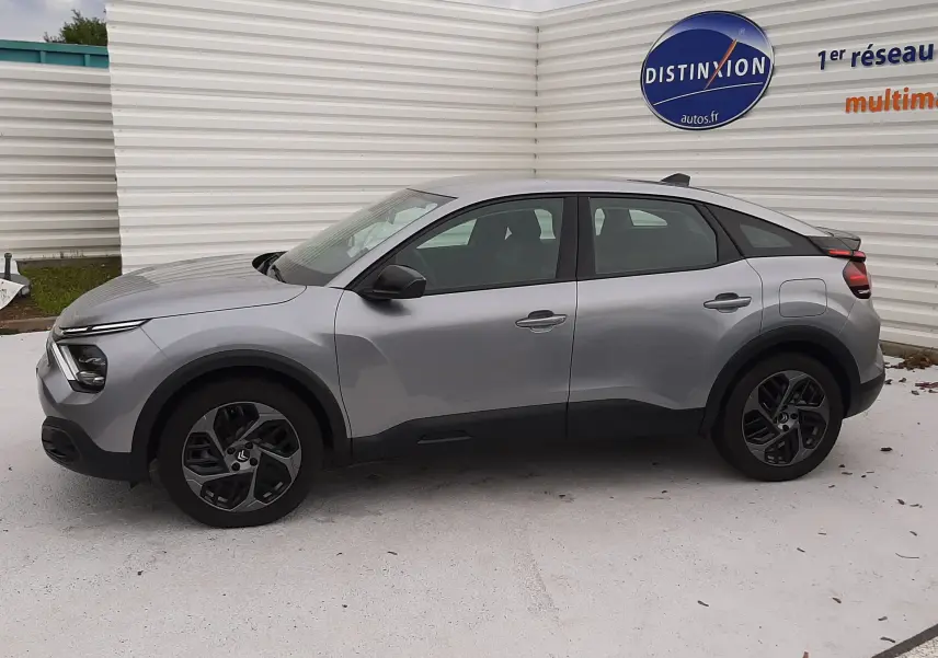 Profil côté gauche d'une Citroën C4 Hybrid 136 gris acier 2024 avec jantes noires et lignes modernes.