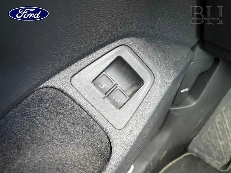 Détail des boutons d’ouverture de trappe à carburant et coffre sur intérieur noir d’un Volkswagen Tiguan.
