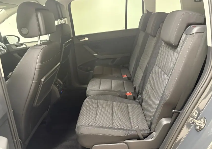 Vue latérale droite de l'intérieur arrière du Volkswagen Touran 2025 gris dauphin avec sièges tissu et appuie-têtes réglables.