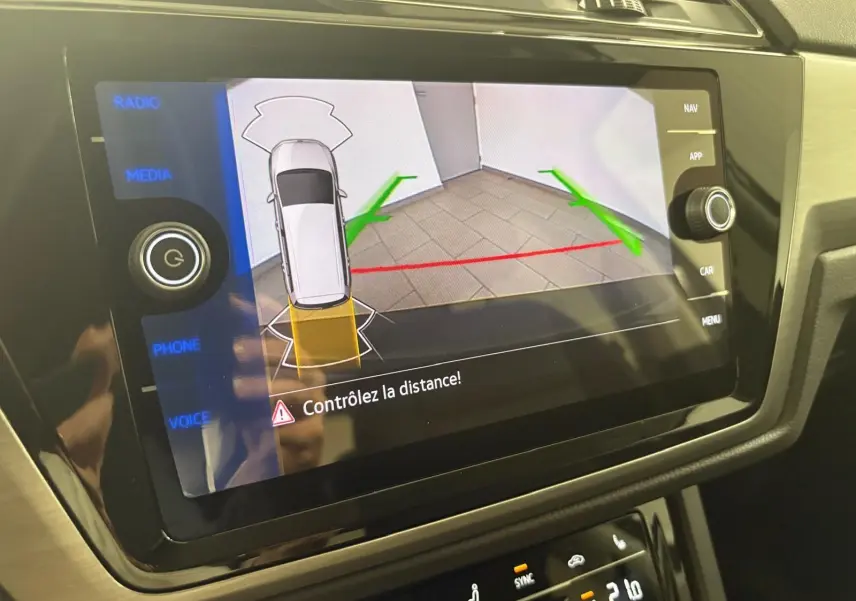 Écran tactile du système multimédia montrant la caméra de recul avec guidage de trajectoire du Volkswagen Touran gris Dauphin.