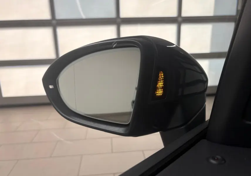 Rétroviseur extérieur côté droit du Volkswagen Touran gris Dauphin 2025 avec clignotant orange allumé.