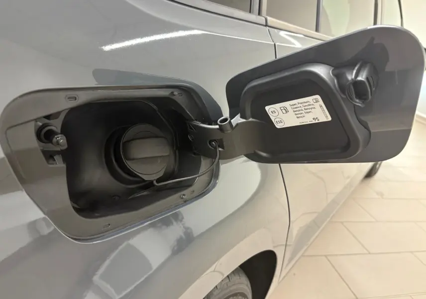 Bouchon de réservoir essence ouvert sur le côté gauche d'un Volkswagen Touran gris dauphin 2025, vue rapprochée.