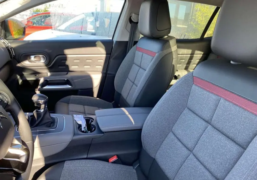 Intérieur avant du Citroën C5 Aircross blanc 2021, sièges gris avec inserts rouges et volant cuir noir.