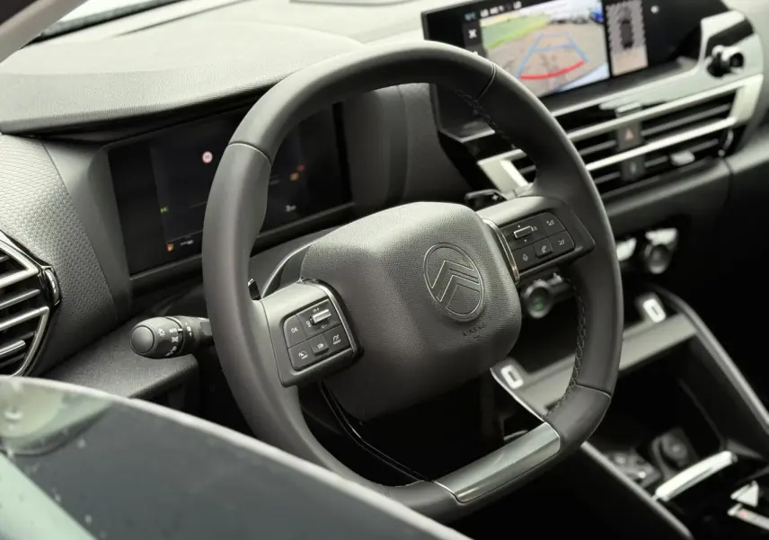 Volant cuir noir avec commandes intégrées dans l'habitacle moderne de la Citroën C4 hybride 2025, vue côté conducteur.