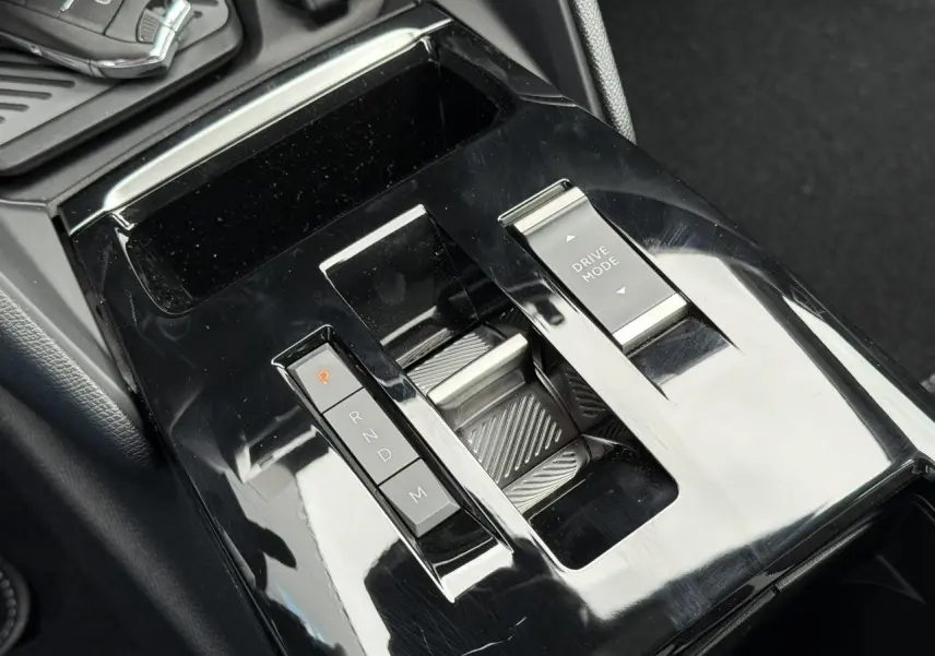 Gros plan sur la console centrale noire brillante du Citroën C4 2025, avec sélecteur de boîte auto et commande Drive Mode.