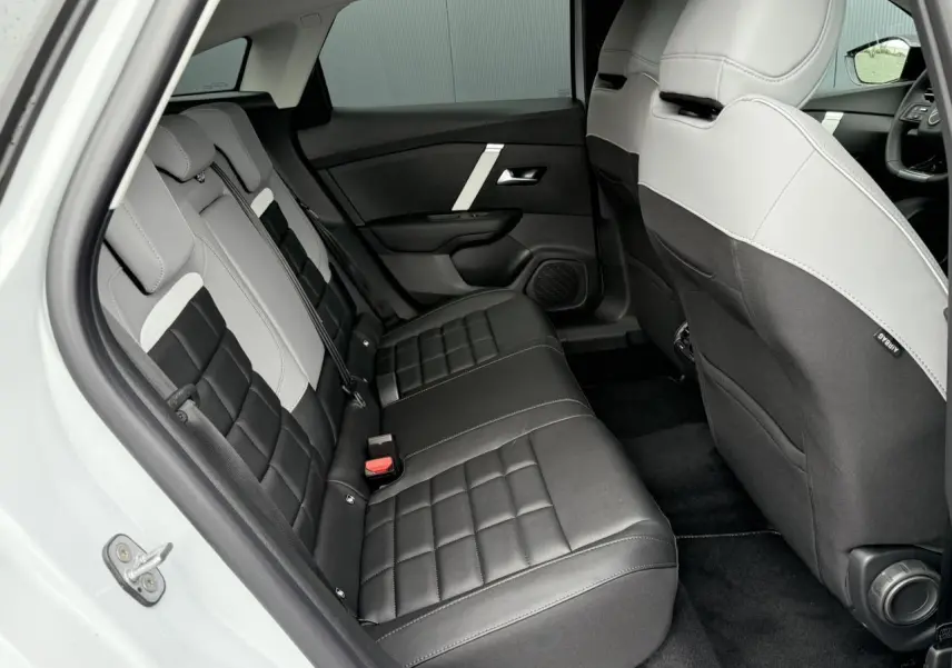 Vue intérieure arrière côté gauche montrant les sièges arrière bicolores noir et gris du Citroën C4 hybride 2025.
