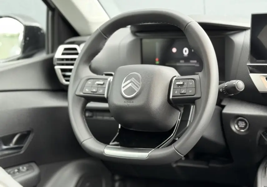 Volant cuir noir de Citroën C4 NV Hybrid 145 e-DSC6 Max 2025 vu de face avec commandes intégrées et tableau de bord numérique.