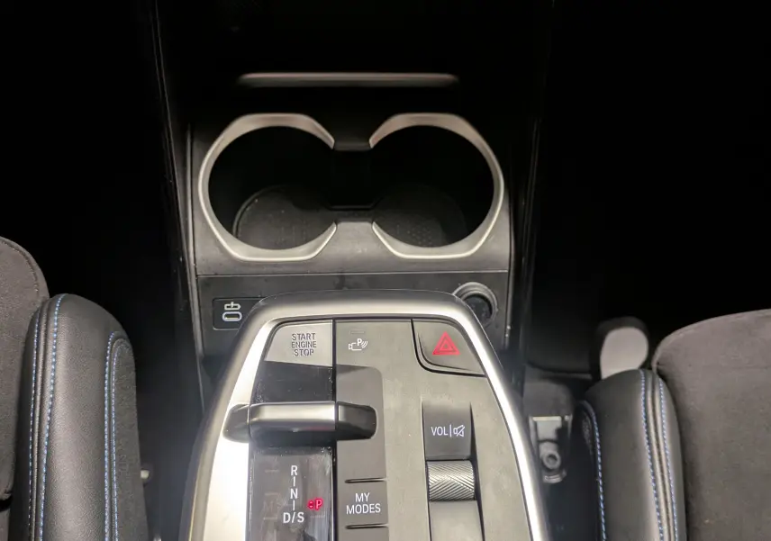 Vue plongeante sur la console centrale du BMW X1 blanc, mettant en valeur le sélecteur de vitesse et les commandes intégrées.