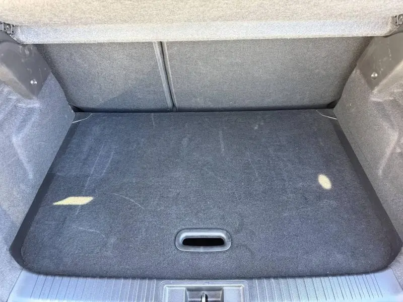 Coffre ouvert vu de face du Renault Captur 2025, intérieur noir avec tapis de sol couvrant l'espace de chargement.