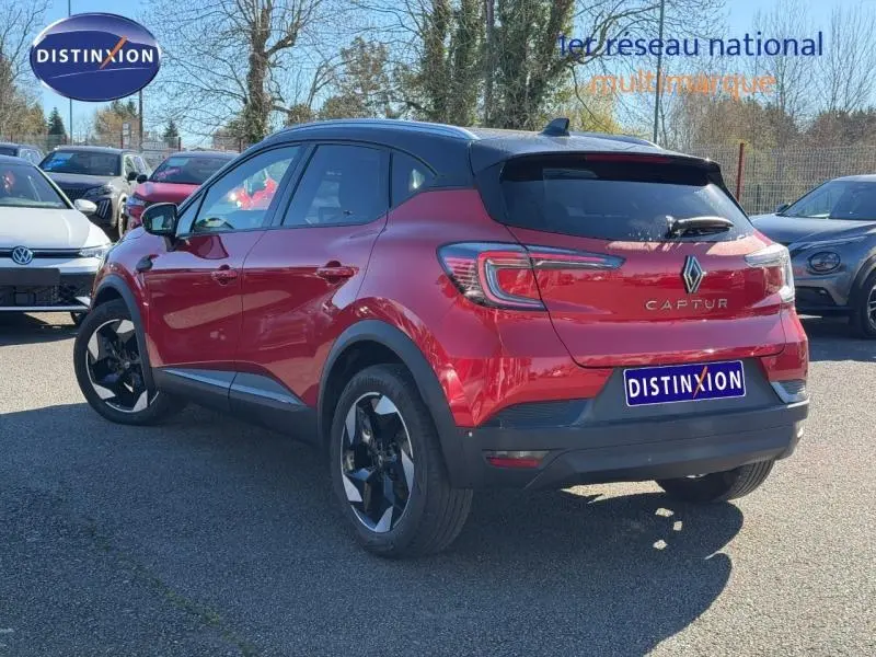 Vue 3/4 arrière droite d'un Renault Captur Rouge Flamme 2025 avec toit noir et jantes noires distinctives.