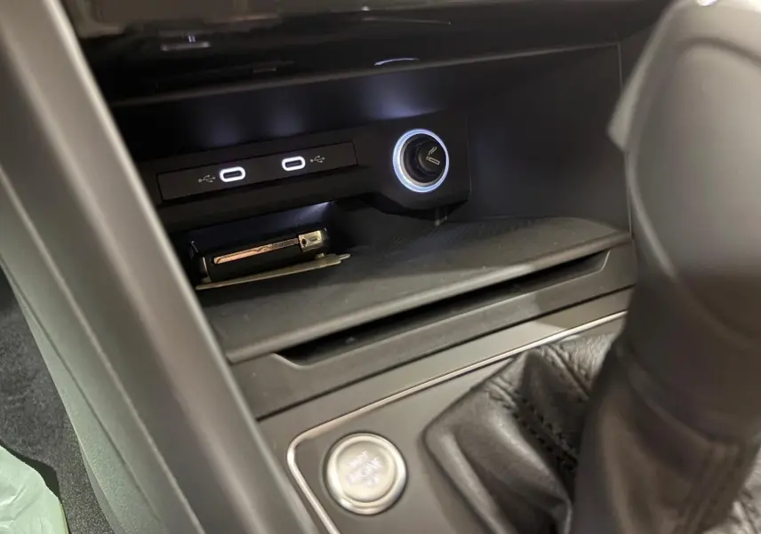 Détail de la console centrale du Volkswagen Touran 2025 avec ports USB, allume-cigare illuminé et bouton start/stop.
