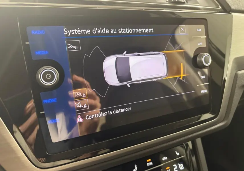Écran tactile intérieur du Volkswagen Touran 2025 montrant le système d'aide au stationnement avec alerte de distance.