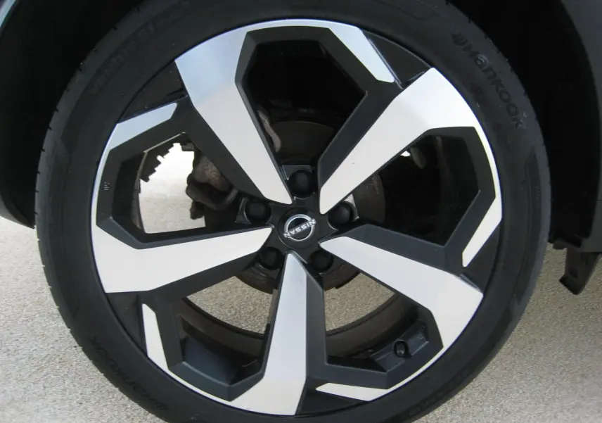 Gros plan sur la jante bi-ton noire et argentée d’un Nissan Juke rouge 2024, mettant en valeur le logo central Nissan.