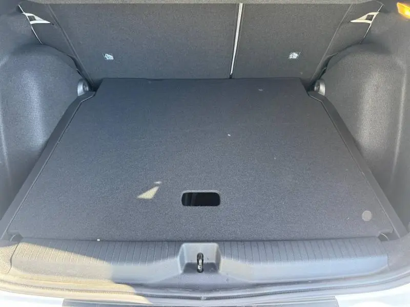 Vue intérieure du coffre fermé du Citroën C3 Aircross 1.2 Hybride blanc, montrant le plancher de coffre plat et noir.