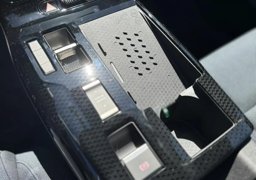 Gros plan sur la console centrale noire à effet carbone du Citroën C5 Aircross NV Hybrid avec commandes de boîte auto et recharge sans fil.