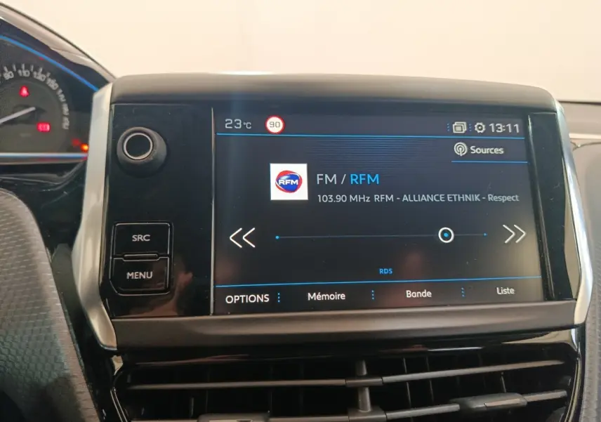 Écran tactile central de la Peugeot 2008 gris foncé affichant la radio FM avec commandes SRC et MENU visibles.