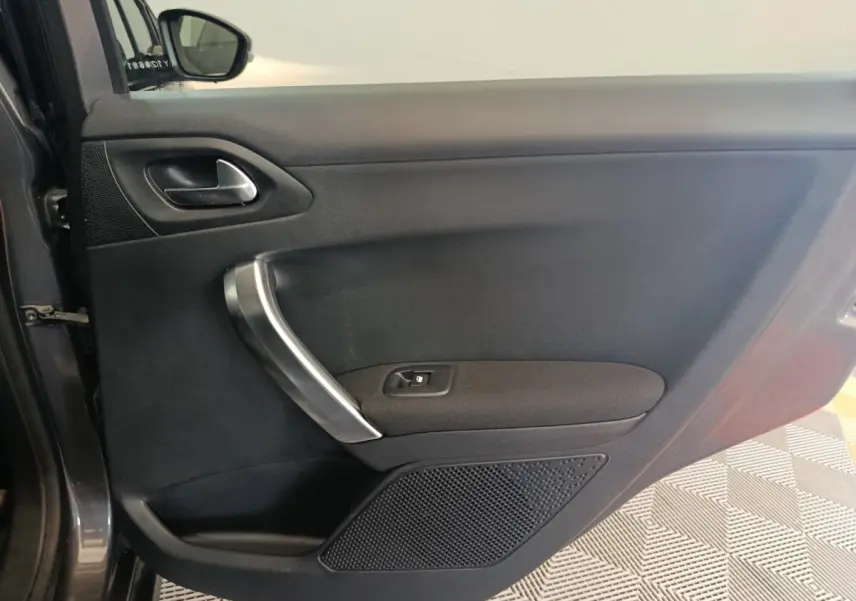 Vue intérieure côté gauche de la porte avant gris foncé du Peugeot 2008 avec poignée argentée et commande de vitre.