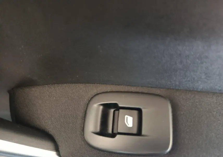 Gros plan sur le bouton de commande de lève-vitre côté conducteur d’un Peugeot 2008 gris foncé.