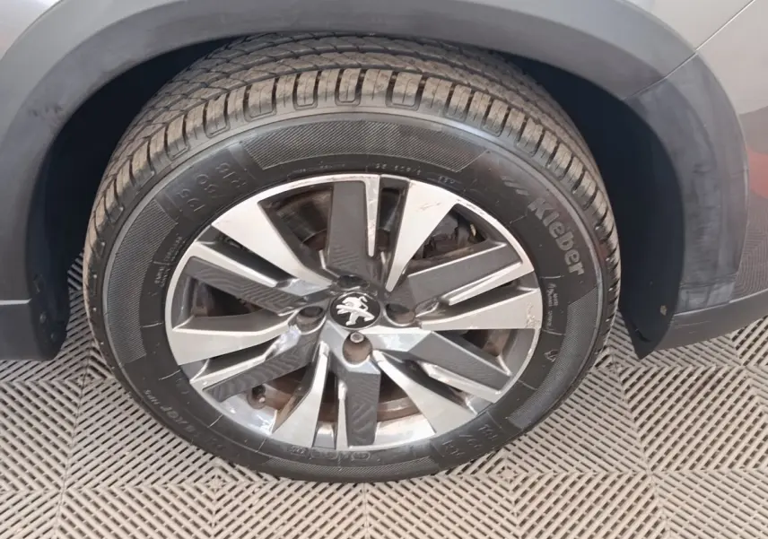 Gros plan sur la roue avant droite d’un Peugeot 2008 gris foncé, avec jante alliage et logo lion au centre.
