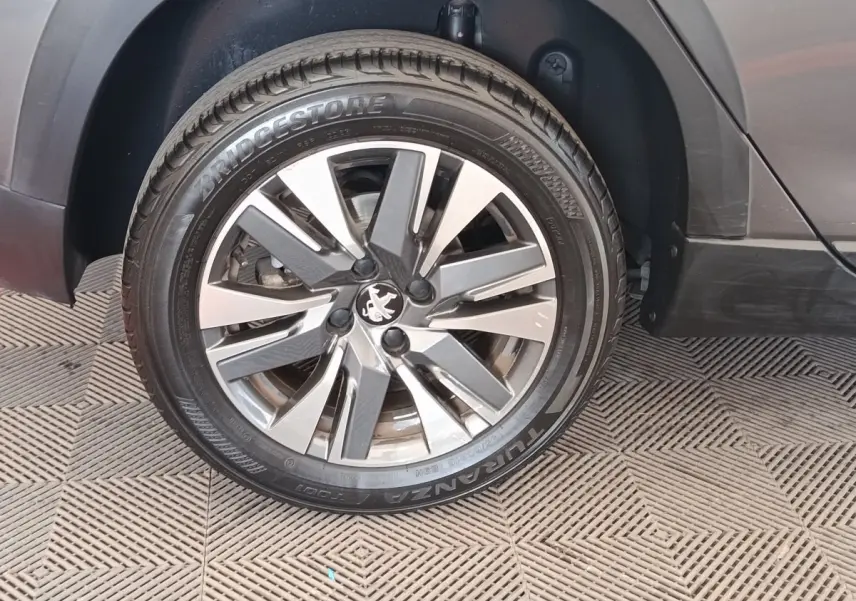 Gros plan sur la roue avant droite d’un Peugeot 2008 gris foncé, avec jante alliage et pneu Bridgestone.