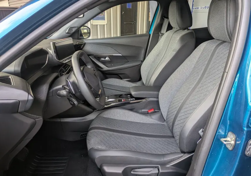 Vue intérieure côté conducteur de la Peugeot 2008 Hybrid 145 Allure bleu obsession, avec sellerie tissu gris et volant multifonction.