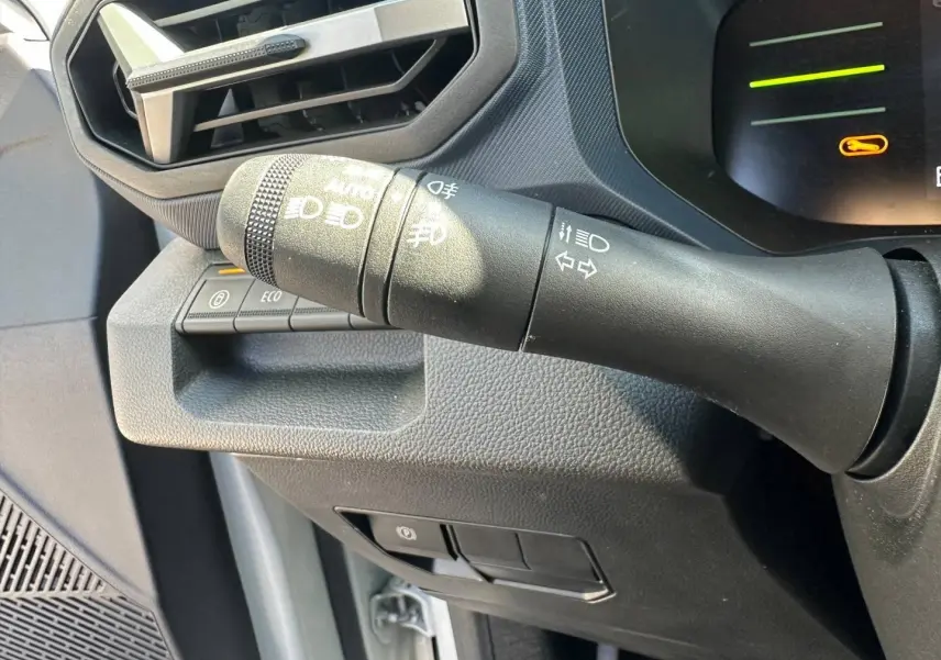 Gros plan sur la commande des feux et clignotants à gauche du tableau de bord du Dacia Duster 2025 couleur Sandstone.