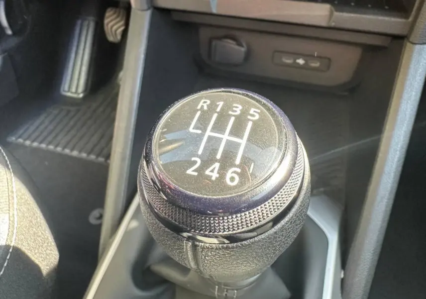 Gros plan sur le levier de vitesses manuel noir du Dacia Duster 1.2 mild hybrid 130ch en intérieur.