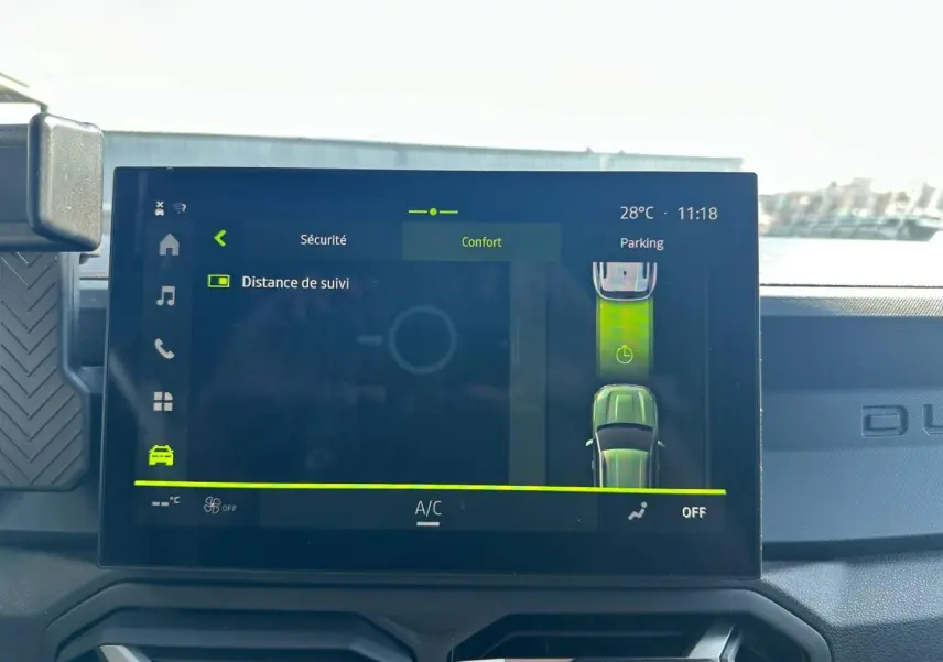 Écran tactile intérieur du Dacia Duster 2025 affichant l'assistance parking et la température à 28°C.