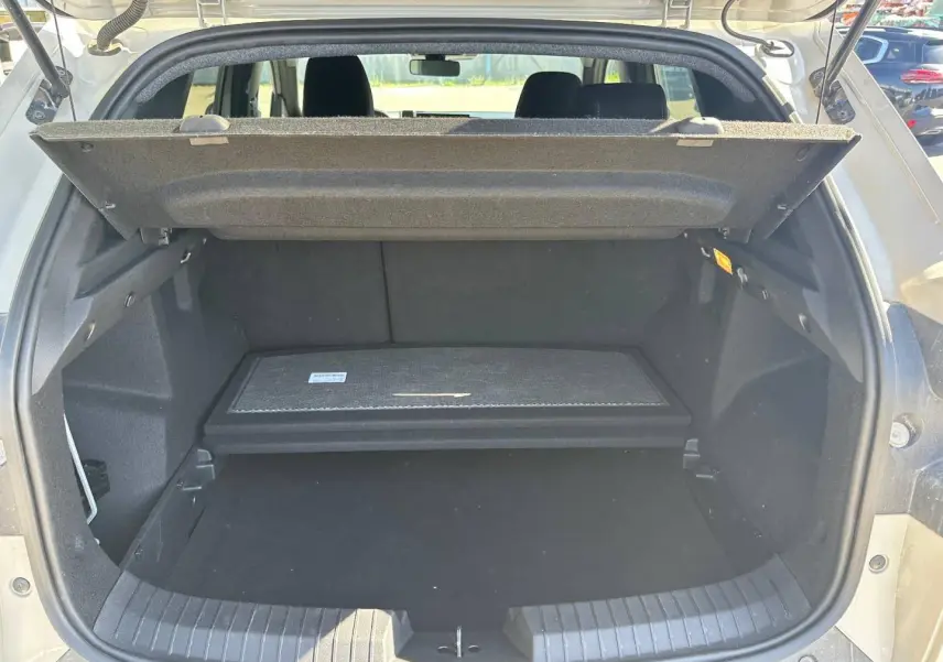 Coffre ouvert du Dacia Duster 2025 Sandstone, montrant la tablette cache-bagages et l’espace de rangement noir.