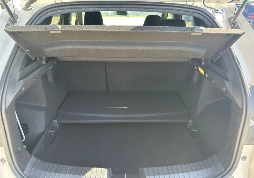 Coffre ouvert du Dacia Duster 2025 Sandstone, montrant le plancher de coffre mobile et l'espace de rangement intérieur.