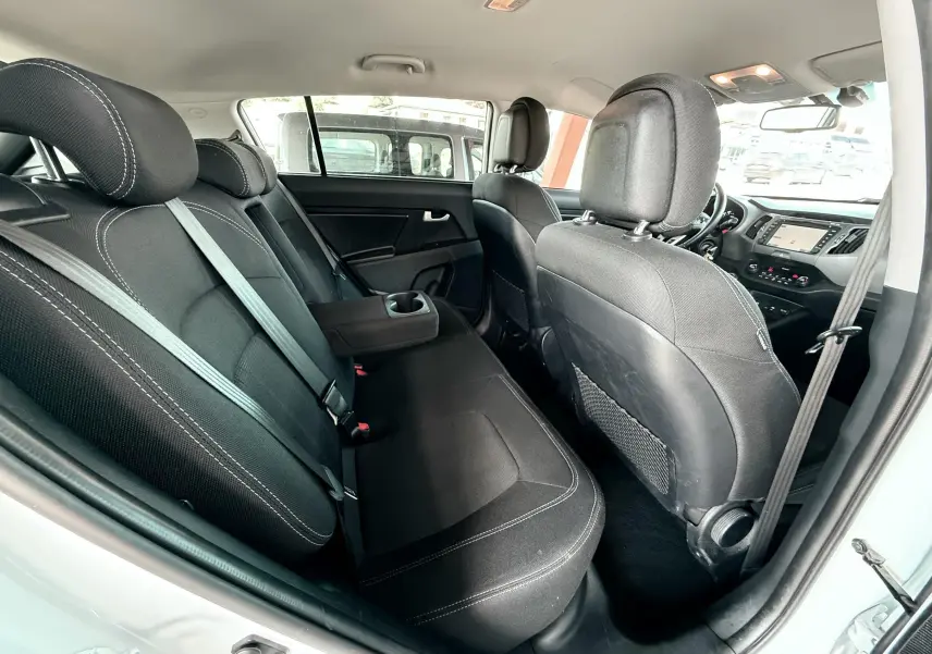 Intérieur arrière du Kia Sportage blanc 2015, vue côté droit montrant les sièges noirs avec accoudoir central relevé.