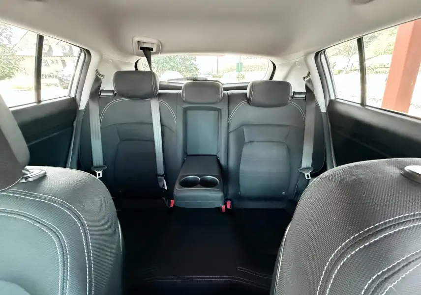 Vue intérieure arrière du Kia Sportage 2015, sièges noirs avec accoudoir central et ceintures visibles.
